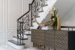 This stunning entryway showcases a beautifully designed staircase with intricate wrought iron detailing, leading to the upper levels of the home.