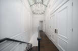 Step into luxury with this stunning hallway, featuring exquisite white paneling and a grand staircase.
