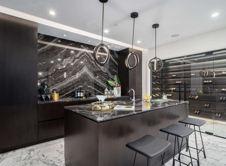 Experience luxury living in this stunning kitchen, featuring a sleek island with seating and modern pendant lighting.
