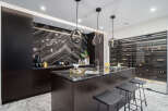 Experience luxury living in this stunning kitchen, featuring a sleek island with seating and modern pendant lighting.