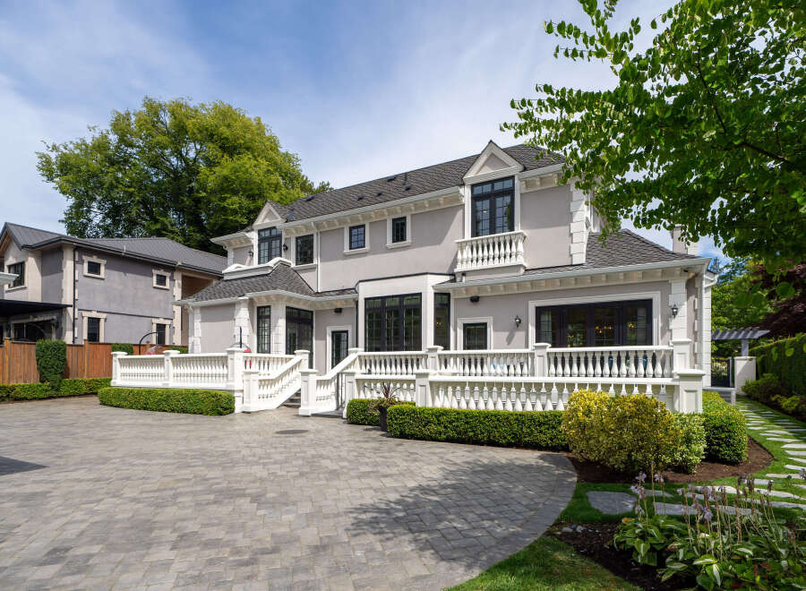 This stunning property boasts a beautifully designed exterior with a paved driveway and lush landscaping.