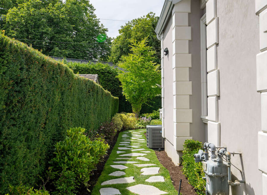 Discover the charm of this beautifully landscaped property, featuring a serene stone pathway that leads through a lush green lawn.