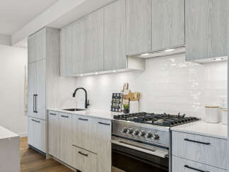This modern kitchen boasts sleek, light-colored wood cabinetry and a pristine white countertop, creating a bright and inviting space.