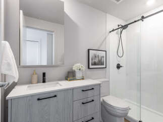 Step into a modern bathroom oasis! This stunning space features a sleek vanity with ample storage, complemented by a stylish black faucet and hardware.