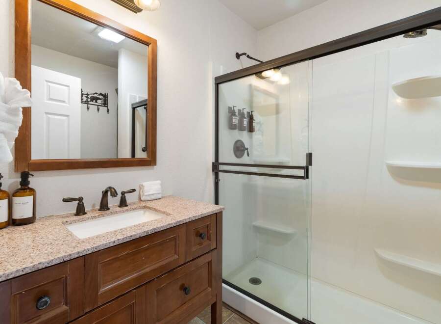 Step into a beautifully designed bathroom featuring a stylish vanity with a granite countertop and a large mirror.