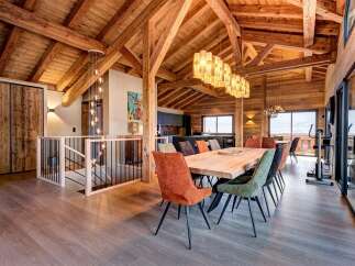 Experience luxury living in this stunning chalet, featuring a spacious open-plan design with exposed wooden beams and a modern kitchen.
