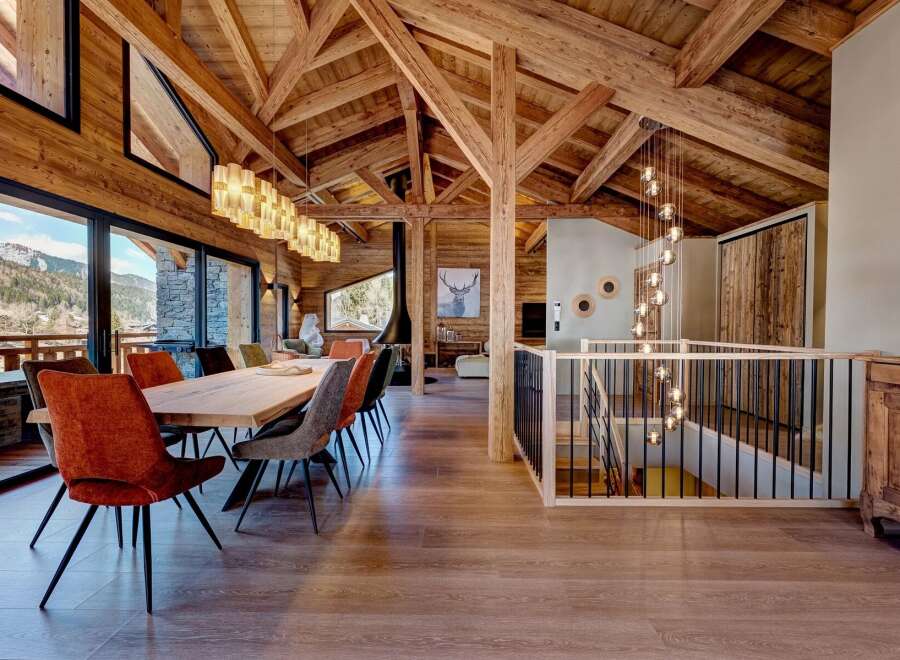 Experience luxury living in this stunning chalet, featuring a spacious dining area with a large wooden table and comfortable seating.