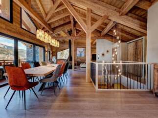 Experience luxury living in this stunning chalet, featuring a spacious dining area with a large wooden table and comfortable seating.