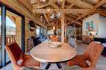 Experience luxury living in this stunning chalet, featuring a warm and inviting interior with exposed wooden beams and a spacious dining area.