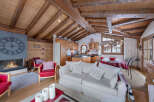 Experience the charm of this stunning chalet, featuring a cozy living room with a fireplace and a rustic wooden ceiling.