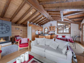 Experience the charm of this stunning chalet, featuring a cozy living room with a fireplace and a rustic wooden ceiling.