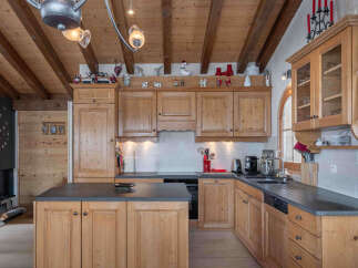 This charming kitchen boasts a warm, inviting atmosphere with its wooden cabinetry and exposed beams.