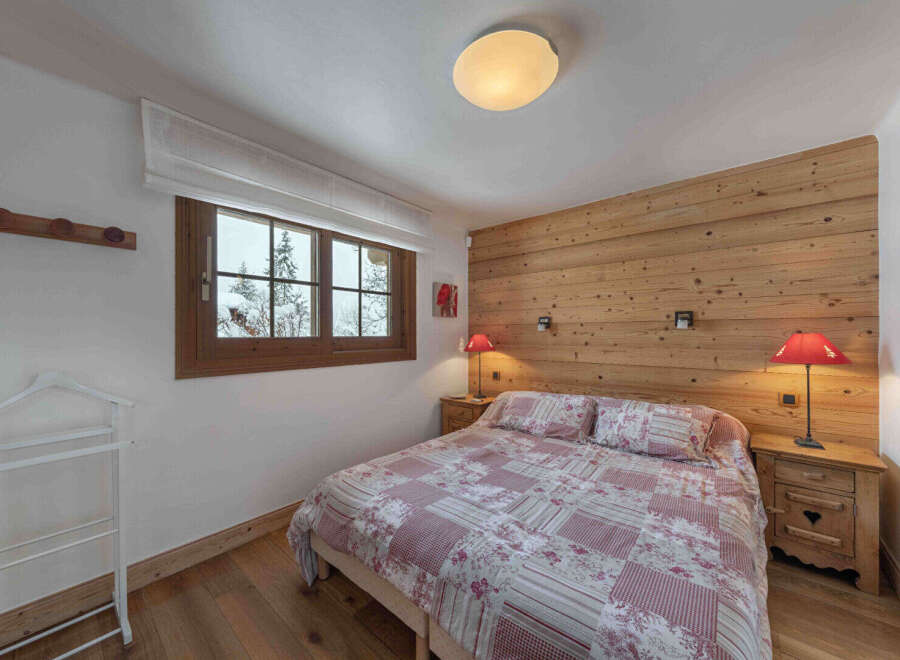 This cozy bedroom features a rustic wooden accent wall and warm wooden flooring, creating a welcoming atmosphere.