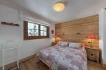 This cozy bedroom features a rustic wooden accent wall and warm wooden flooring, creating a welcoming atmosphere.