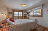 Experience the charm of this cozy bedroom, featuring a warm wooden interior and a stunning view of a snowy landscape.