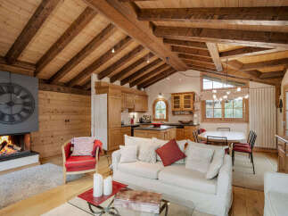 Experience rustic charm in this inviting living space, featuring a grand fireplace with a striking clock and exposed wooden beams that enhance the cozy ambiance.