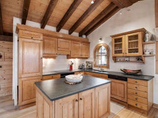 Experience rustic charm in this beautifully appointed wooden kitchen, featuring a vaulted ceiling with exposed beams and ample natural light.