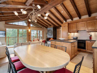 Experience rustic charm in this open-plan living space, featuring a cozy fireplace and a fully equipped wooden kitchen.