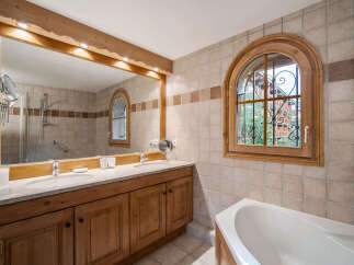 This charming bathroom features a double vanity with ample counter space and wooden cabinetry, perfect for storage.