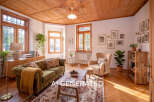 Step into this charming living room featuring a plush green tufted sofa adorned with a cozy yellow throw, complemented by a rustic wooden coffee table.