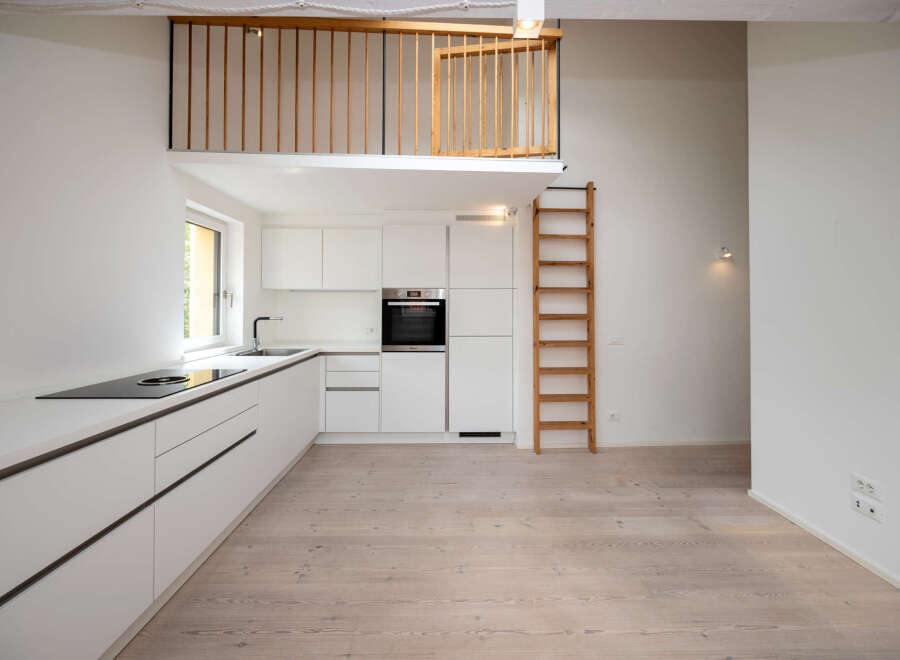 This modern kitchen features sleek white cabinetry and a built-in oven, creating a clean and minimalist aesthetic.