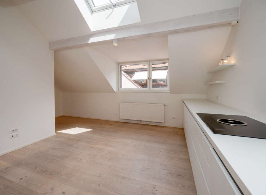Discover this bright and airy apartment featuring a modern kitchen with sleek white cabinetry and a built-in cooktop.