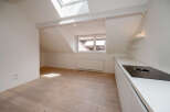 Discover this bright and airy apartment featuring a modern kitchen with sleek white cabinetry and a built-in cooktop.