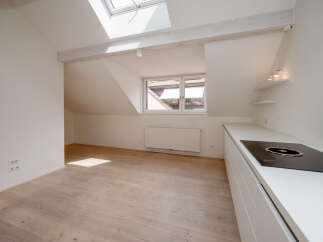 Discover this bright and airy apartment featuring a modern kitchen with sleek white cabinetry and a built-in cooktop.