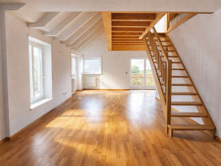 Discover this spacious, light-filled room featuring a beautiful wooden staircase leading to an upper level.