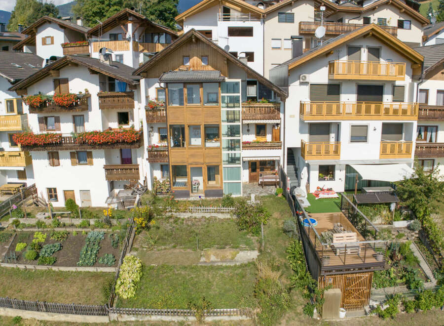 Discover this charming multi-story home featuring multiple balconies adorned with vibrant flowers, perfect for enjoying the scenic surroundings.
