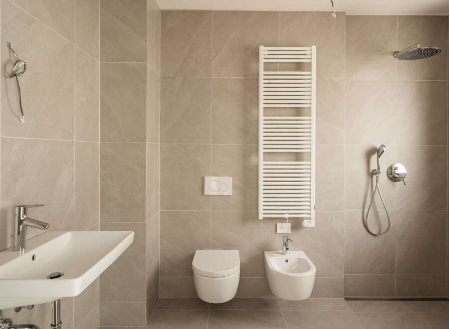 Experience modern luxury in this impeccably designed bathroom, featuring a sleek wall-mounted sink with chrome fixtures and a spacious walk-in shower.