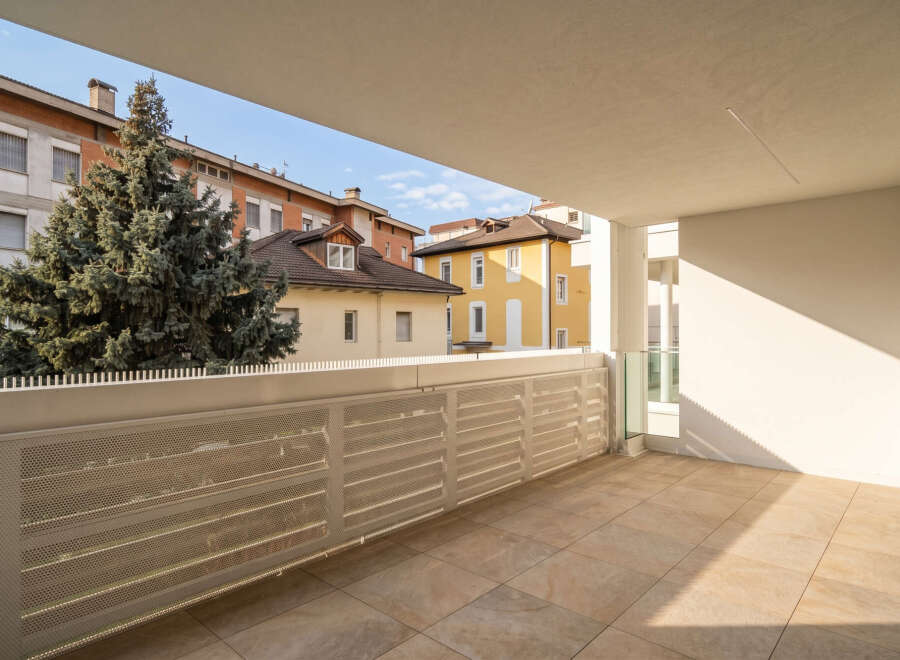 Enjoy the outdoors from this spacious balcony, featuring a modern tiled floor and a sleek metal railing offering a partial view of the surrounding urban landscape.