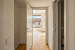 Step into a bright and airy hallway with gleaming hardwood floors that lead to a spacious balcony overlooking a charming neighborhood.