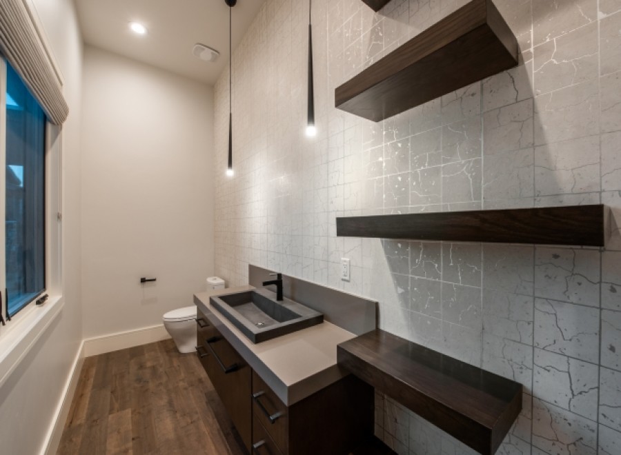 This stunning bathroom boasts a modern design with sleek dark wood floating shelves and a contemporary concrete sink vanity.