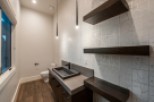 This stunning bathroom boasts a modern design with sleek dark wood floating shelves and a contemporary concrete sink vanity.