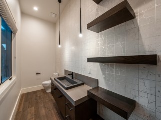 This stunning bathroom boasts a modern design with sleek dark wood floating shelves and a contemporary concrete sink vanity.