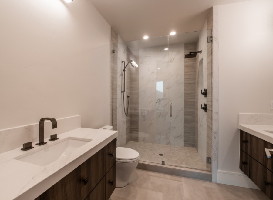 This stunning bathroom boasts a spacious shower with glass enclosure, marble tile, and modern fixtures.