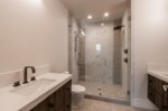 This stunning bathroom boasts a spacious shower with glass enclosure, marble tile, and modern fixtures.