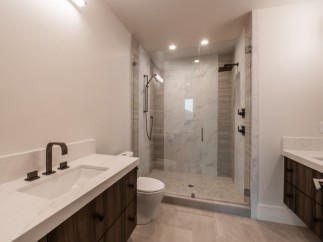 This stunning bathroom boasts a spacious shower with glass enclosure, marble tile, and modern fixtures.