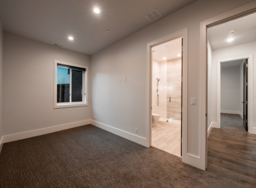 This stunning bedroom boasts a spacious layout with plush carpeting and large windows offering ample natural light.