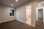 This stunning bedroom boasts a spacious layout with plush carpeting and large windows offering ample natural light.