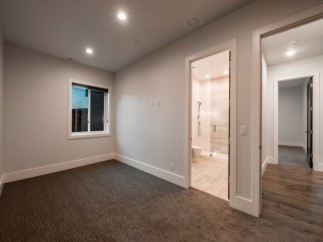 This stunning bedroom boasts a spacious layout with plush carpeting and large windows offering ample natural light.