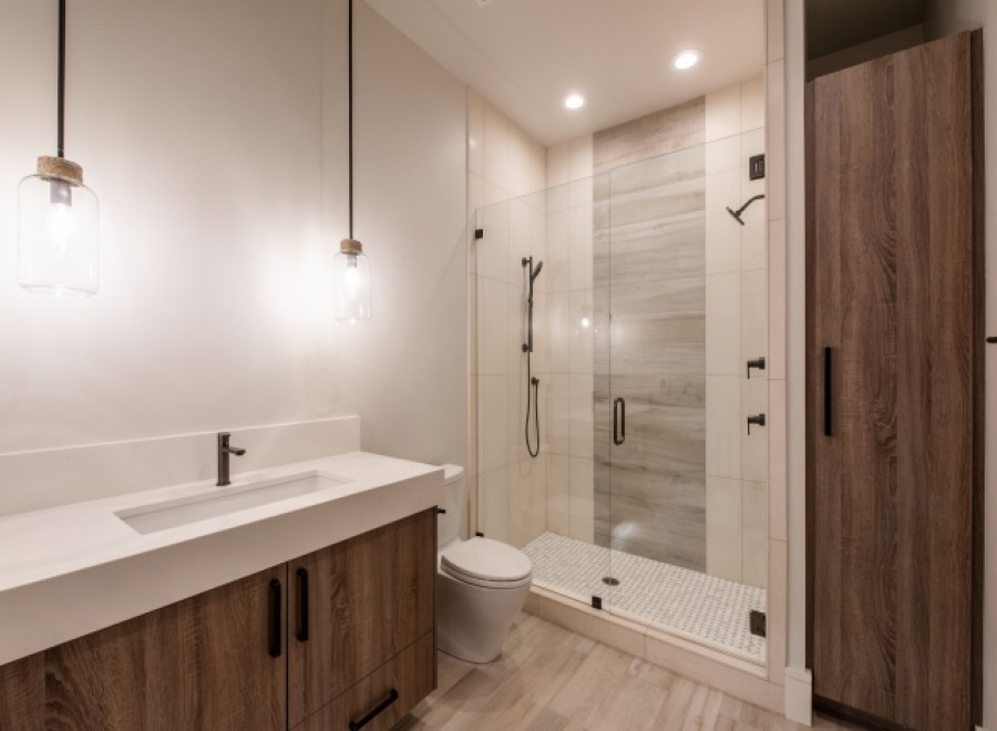 This stunning bathroom boasts a modern design with a sleek white vanity and wood cabinets.