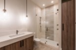 This stunning bathroom boasts a modern design with a sleek white vanity and wood cabinets.