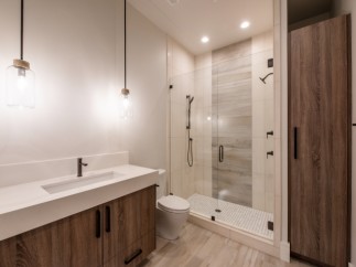 This stunning bathroom boasts a modern design with a sleek white vanity and wood cabinets.