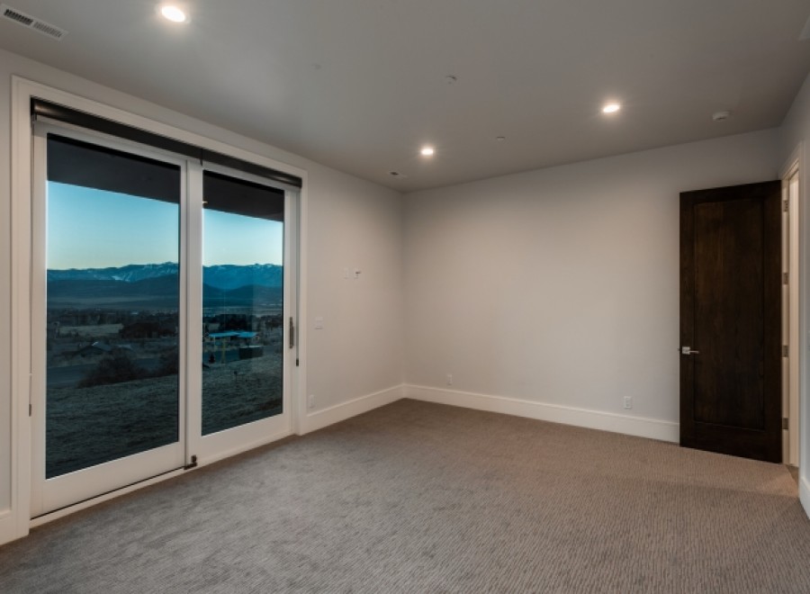 This stunning bedroom boasts a wall of sliding glass doors offering breathtaking mountain views.