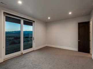 This stunning bedroom boasts a wall of sliding glass doors offering breathtaking mountain views.