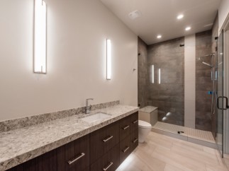 This luxurious bathroom boasts a spacious walk-in shower with modern gray tile and glass enclosure.