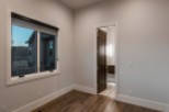 This stunning bedroom boasts a large window with a modern roller shade, offering ample natural light and views of the surrounding landscape.