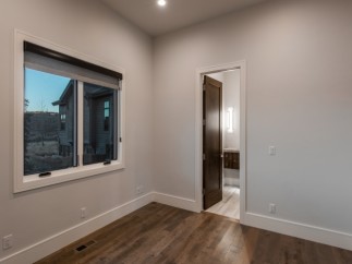 This stunning bedroom boasts a large window with a modern roller shade, offering ample natural light and views of the surrounding landscape.